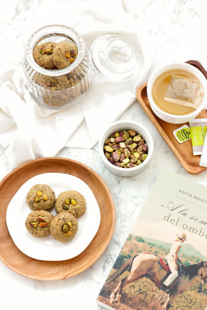 Gluten-free pistachio cookies on marble board with a book.