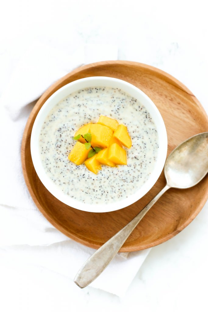 Top down view of a bowl of mango chia seed pudding on a wooden plate.