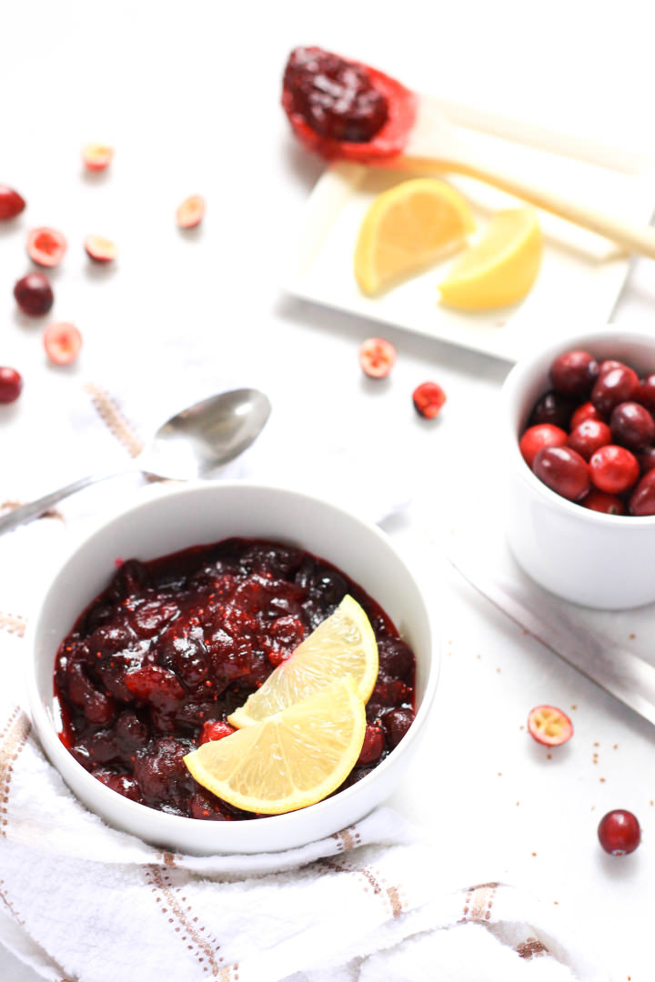 A bowl of gluten-free cranberry sauce with fresh cranberries at the side.