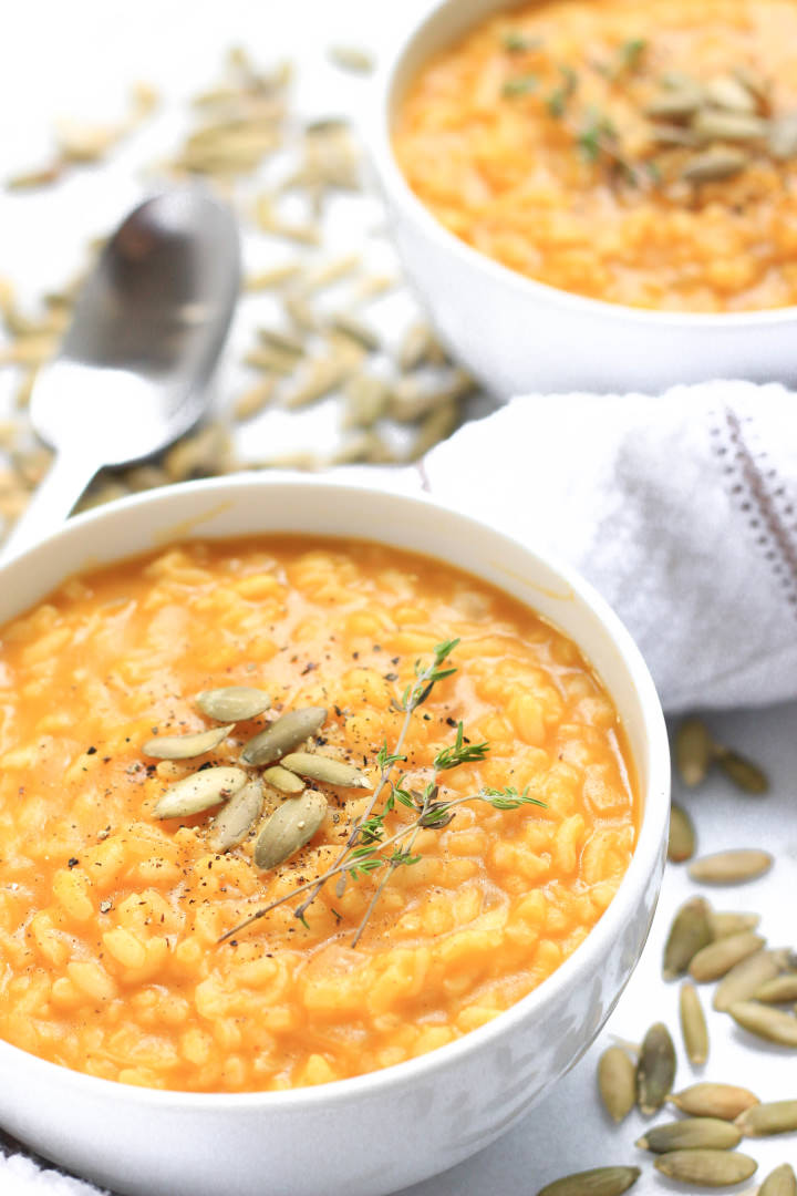 Up close shot of a bowl of vegan pumpkin risotto sprinkled with pumpkin seeds.