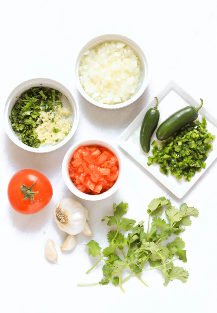 Ingredients for homemade salsa fresca laid out on marble board.