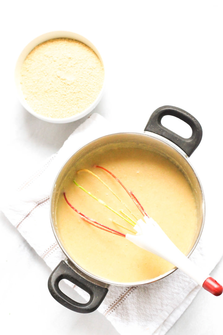 A pot with polenta and a whisk.