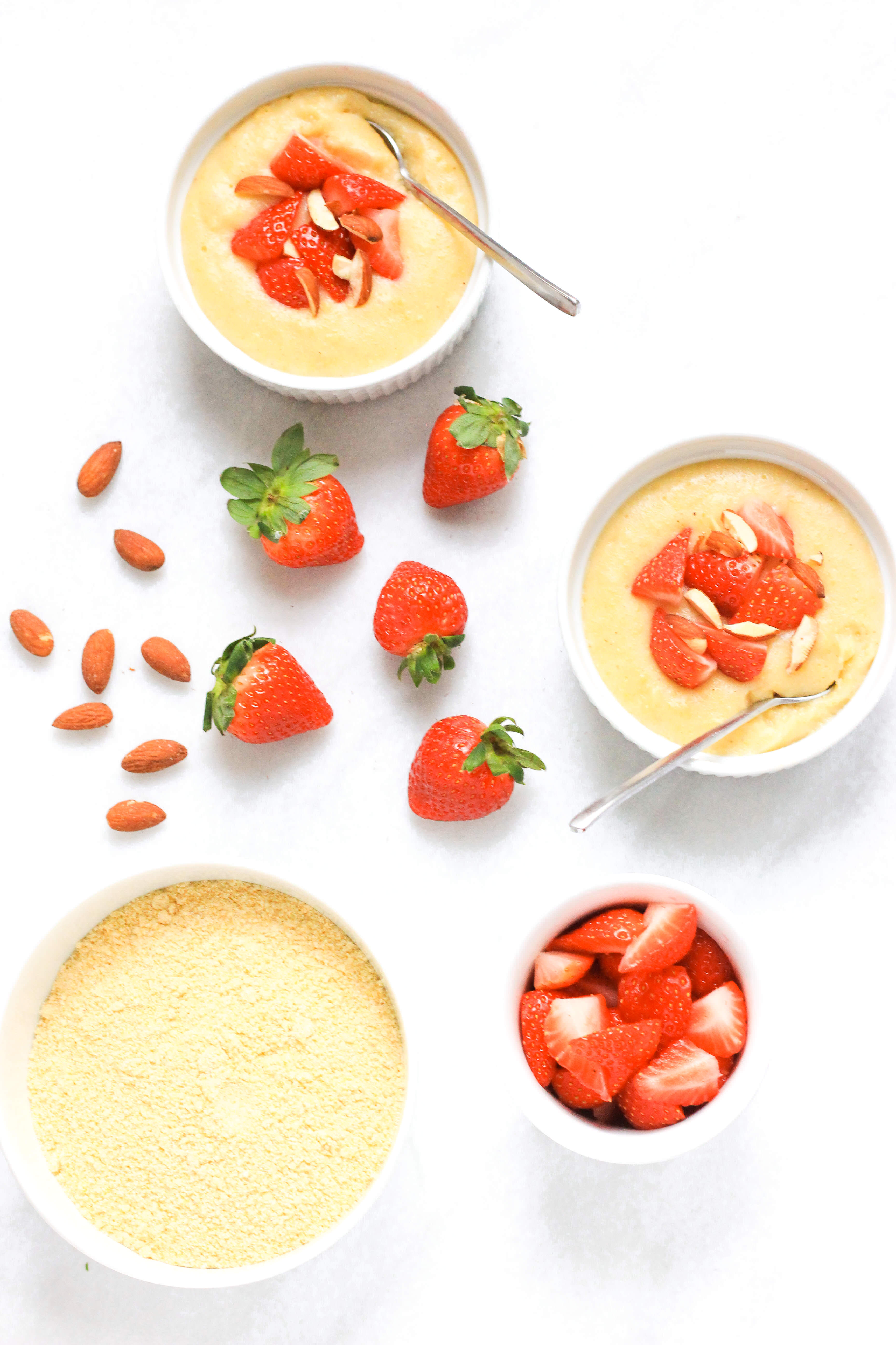 Creamy breakfast polenta in ramekins topped with strawberries and almonds.