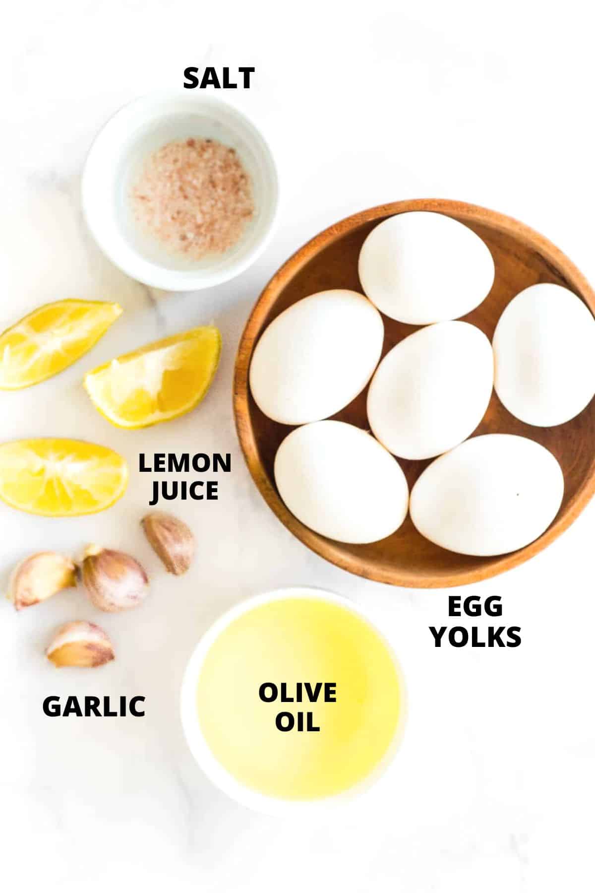 Ingredients for easy garlic aioli recipe laid out on a marble board.