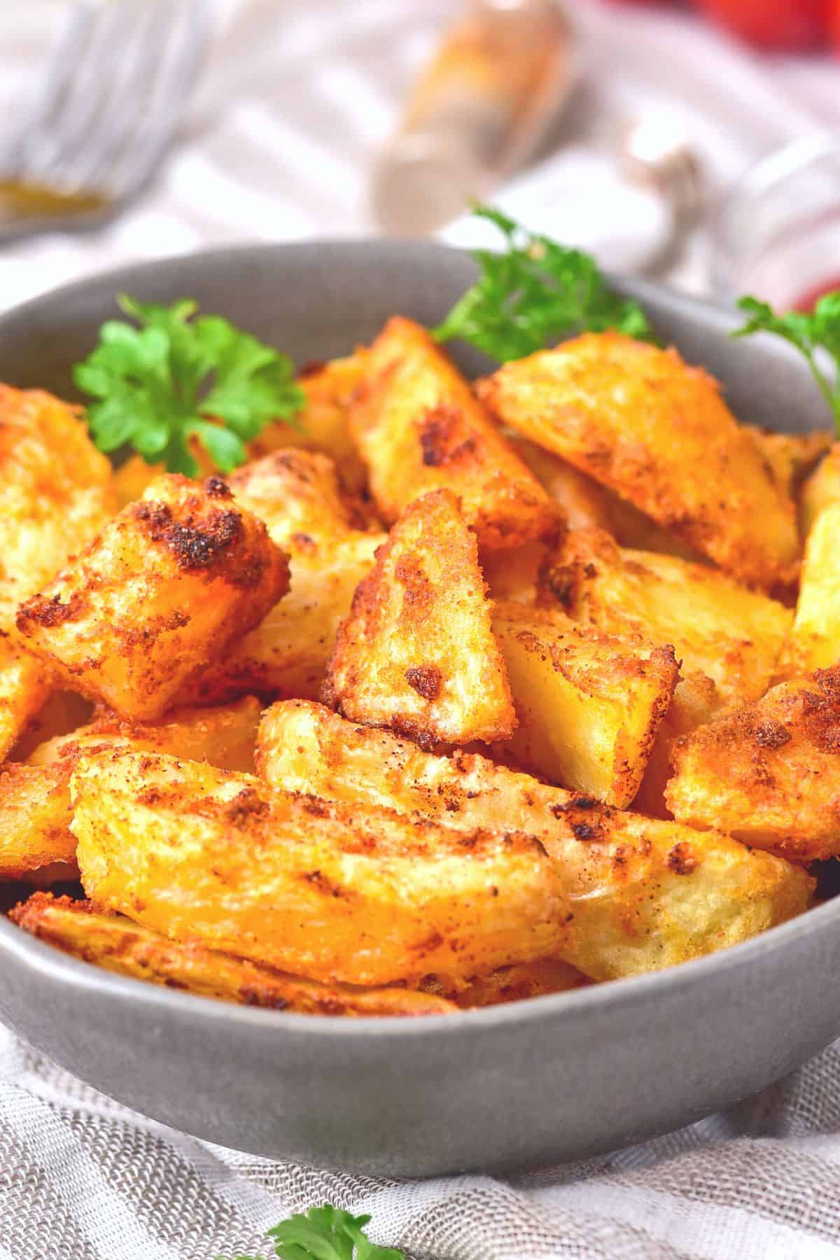 A bowl of crispy air fried potato wedges garnished with parsely.