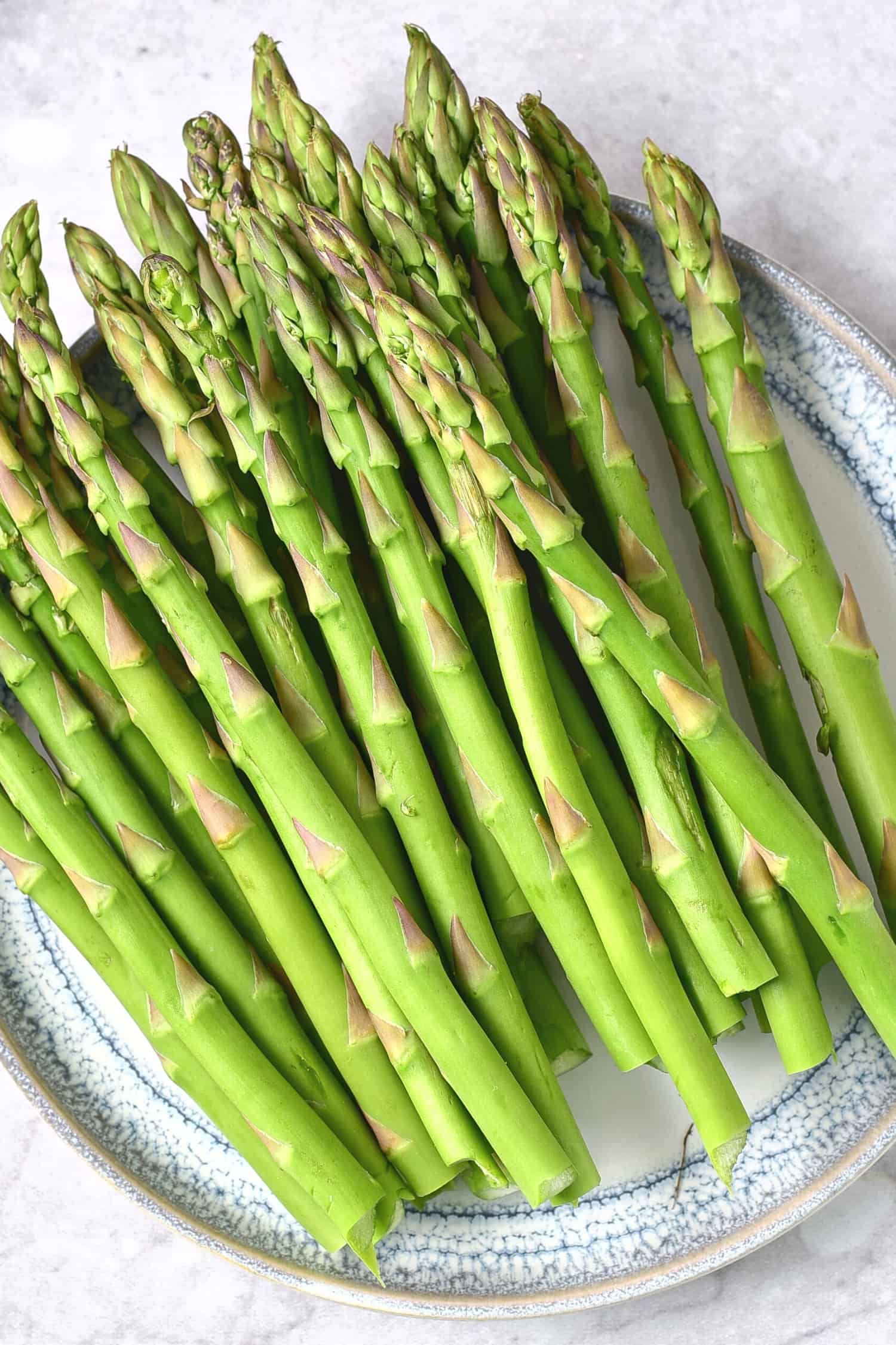 Uncooked asparagus spears on plate.