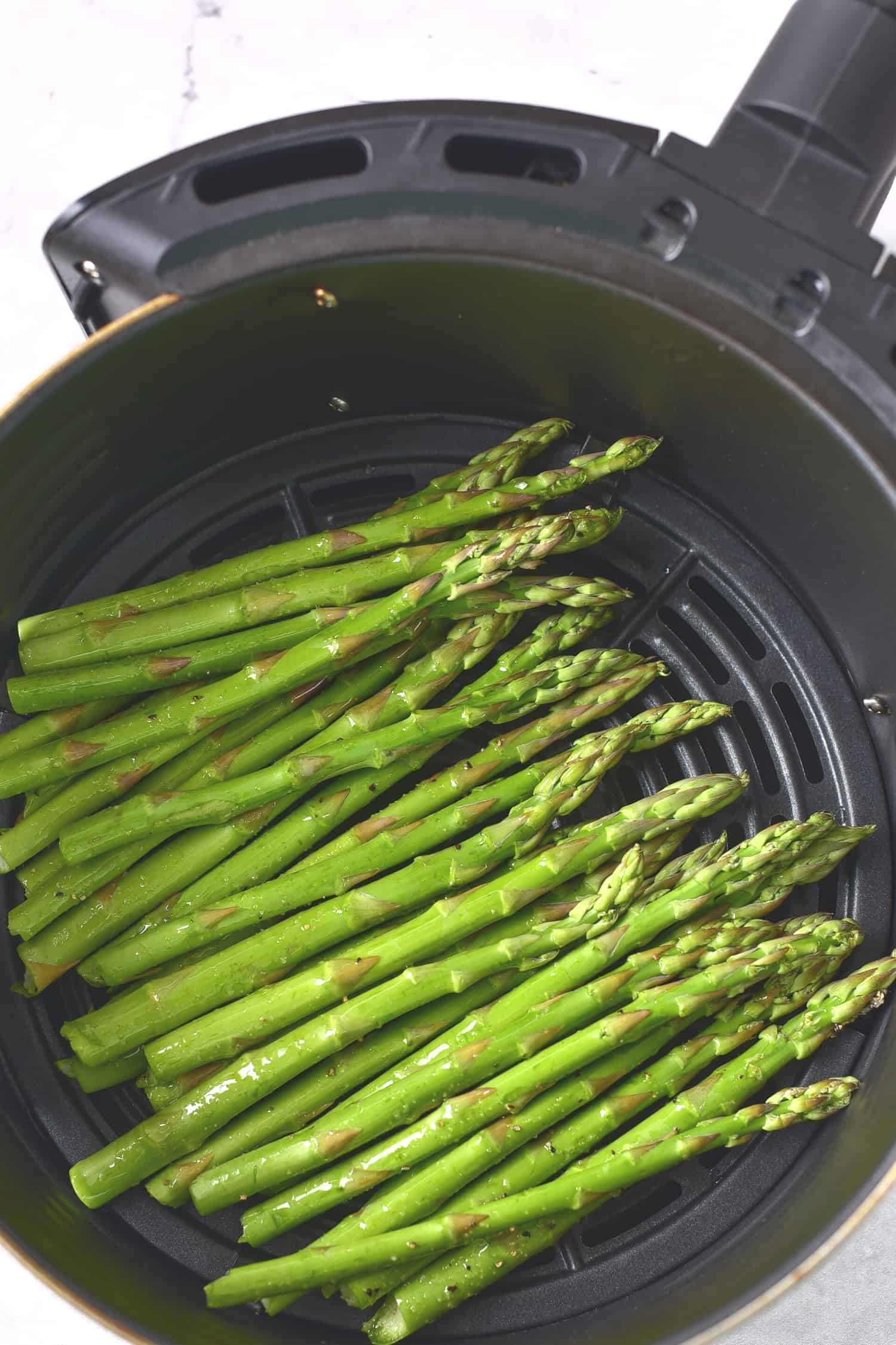 Asparagus stalks in air fryer basket.