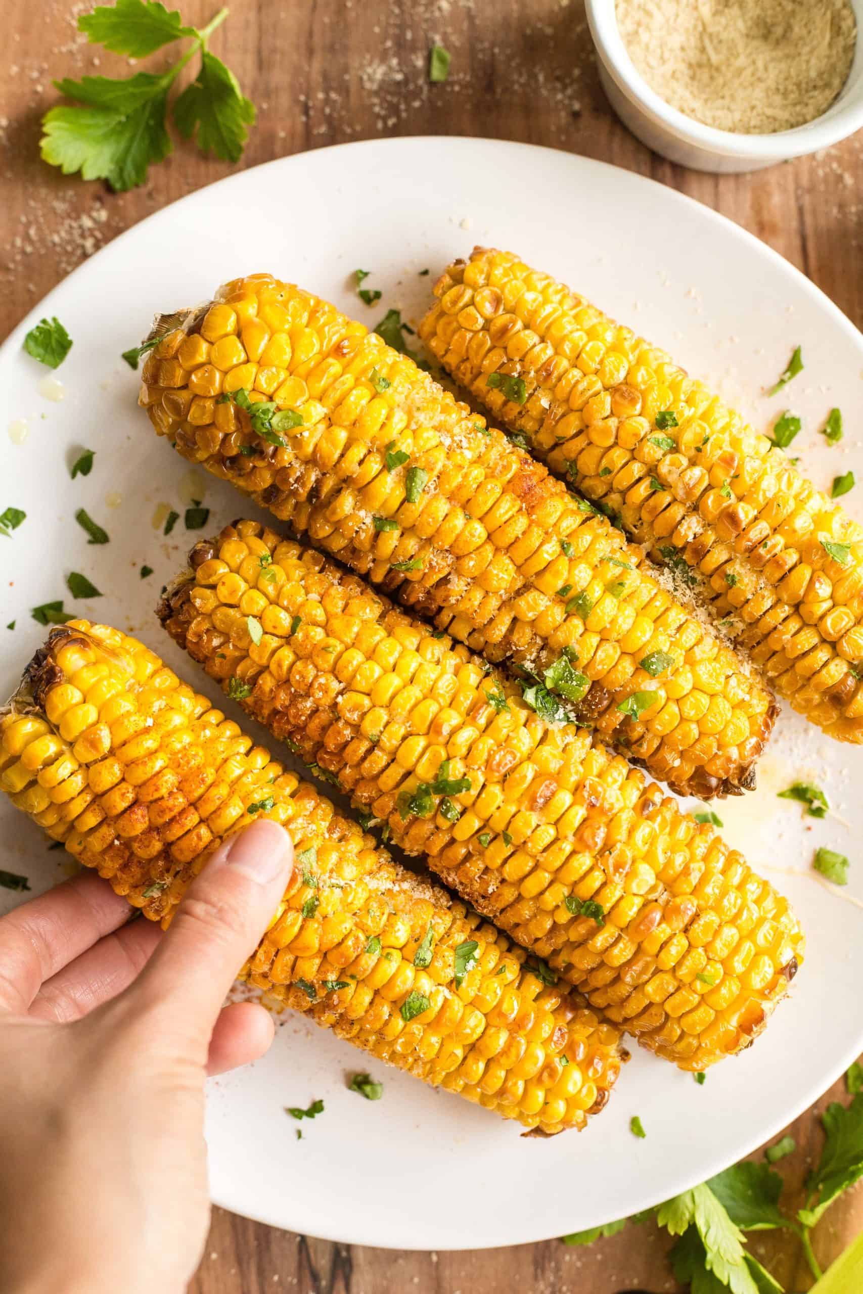 Hand holding a freshly air fried corn on the cob.