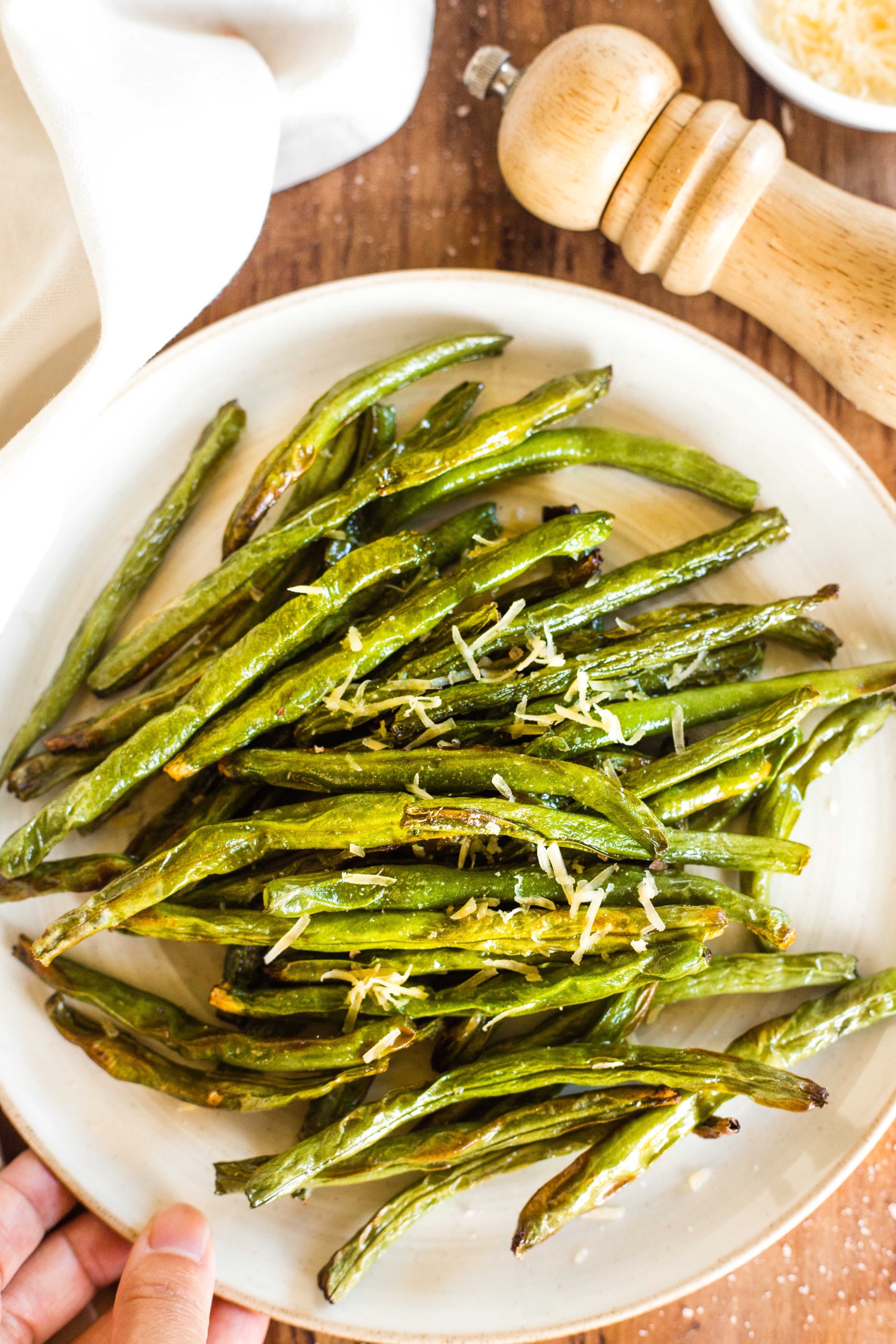 A plate of air fryer green beans on wooden board.