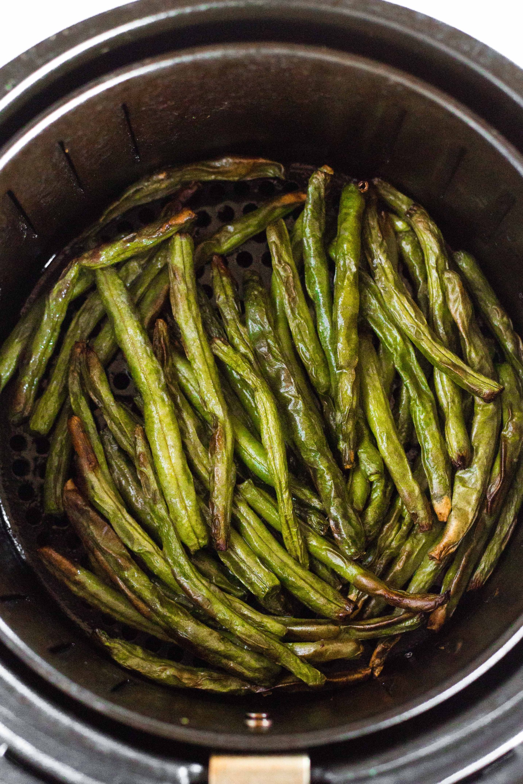 Gluten-free green beans in an air fryer basket.