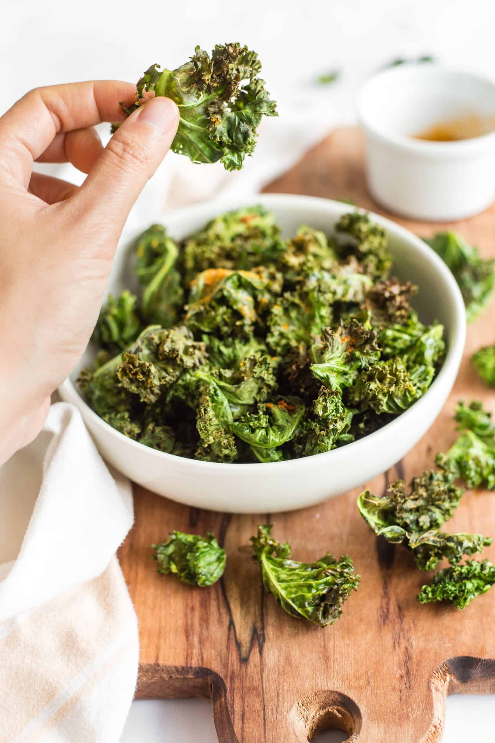 Holding up a kale chip from a bowl.