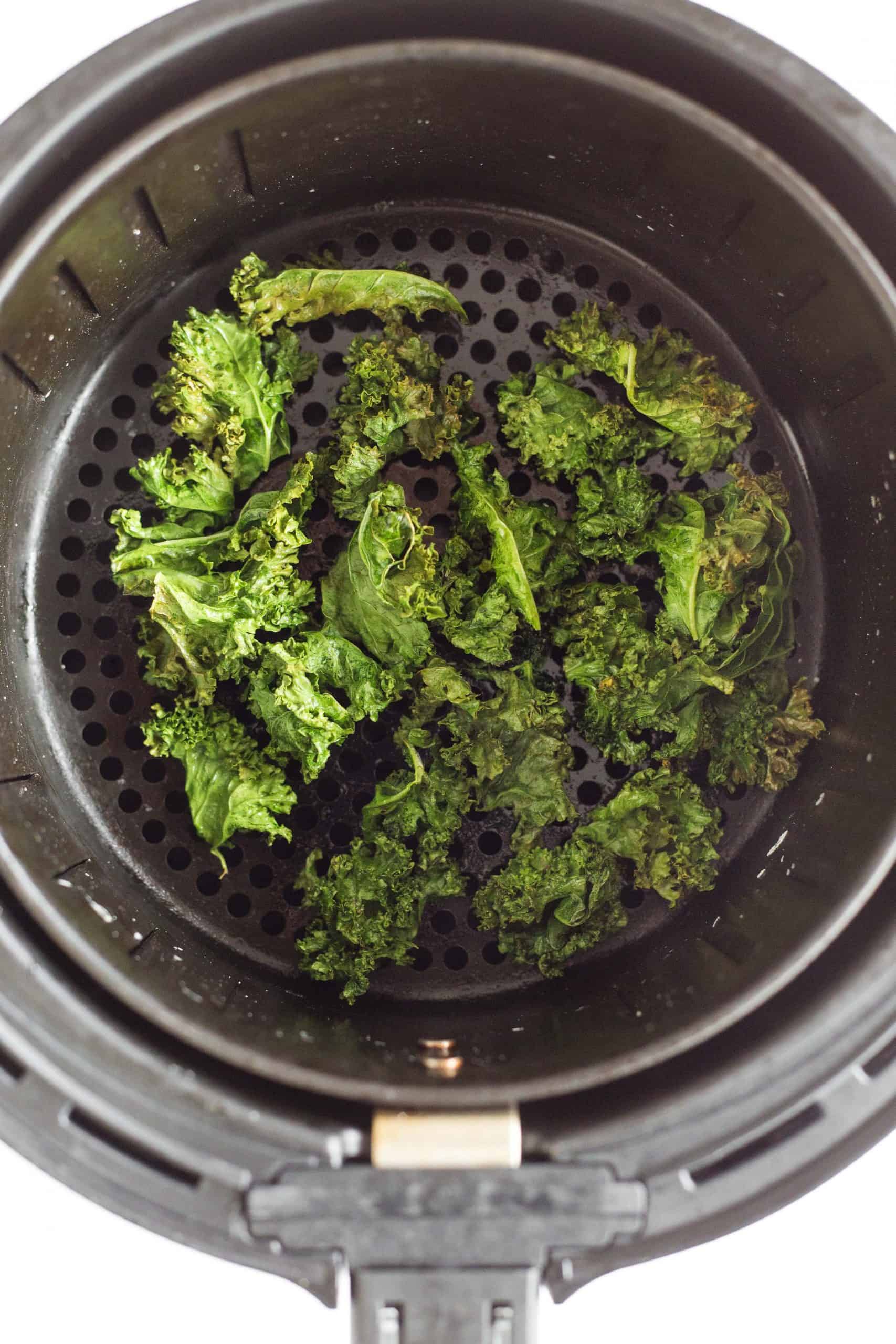Air fried kale chips in the air fryer basket.