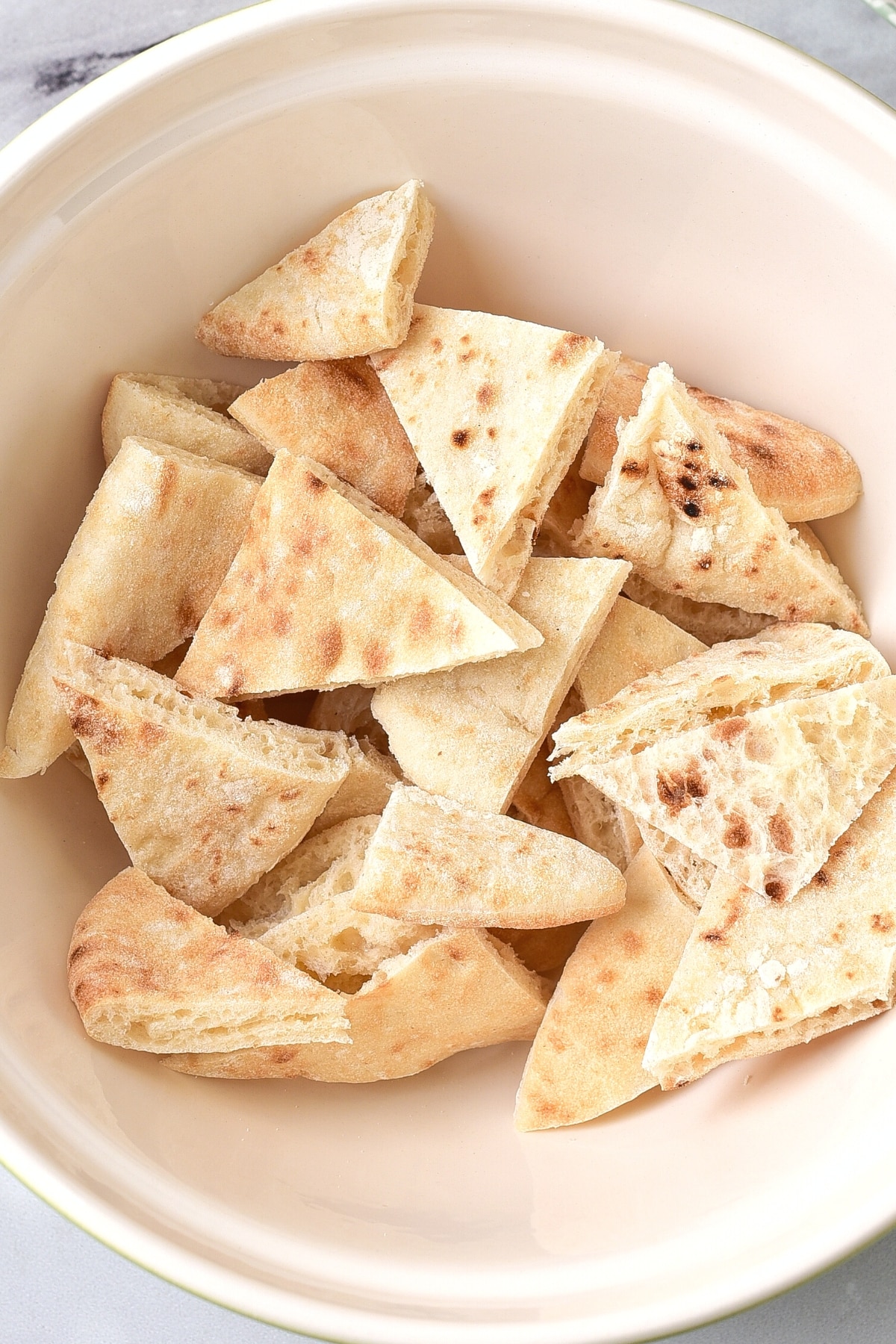 Cut pita triangles in white bowl.