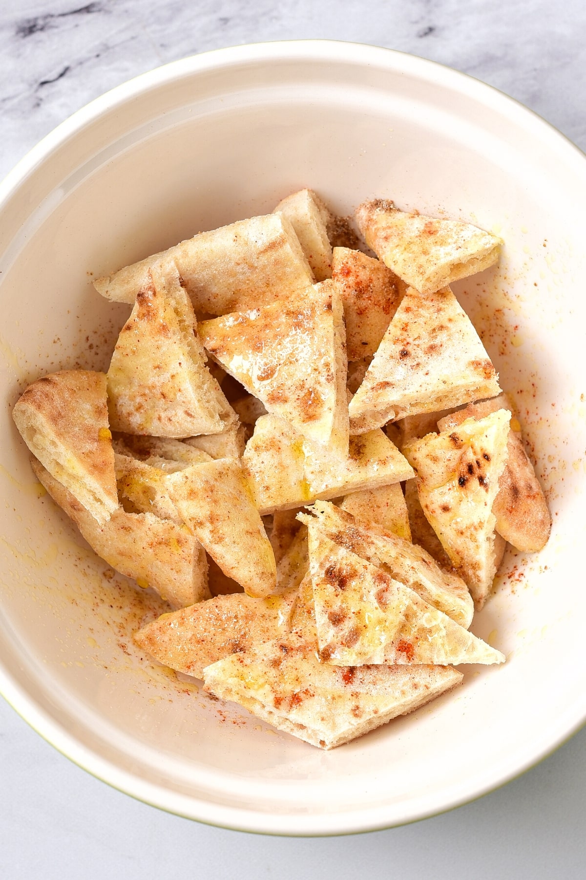 Seasoned pita chips in white bowl.