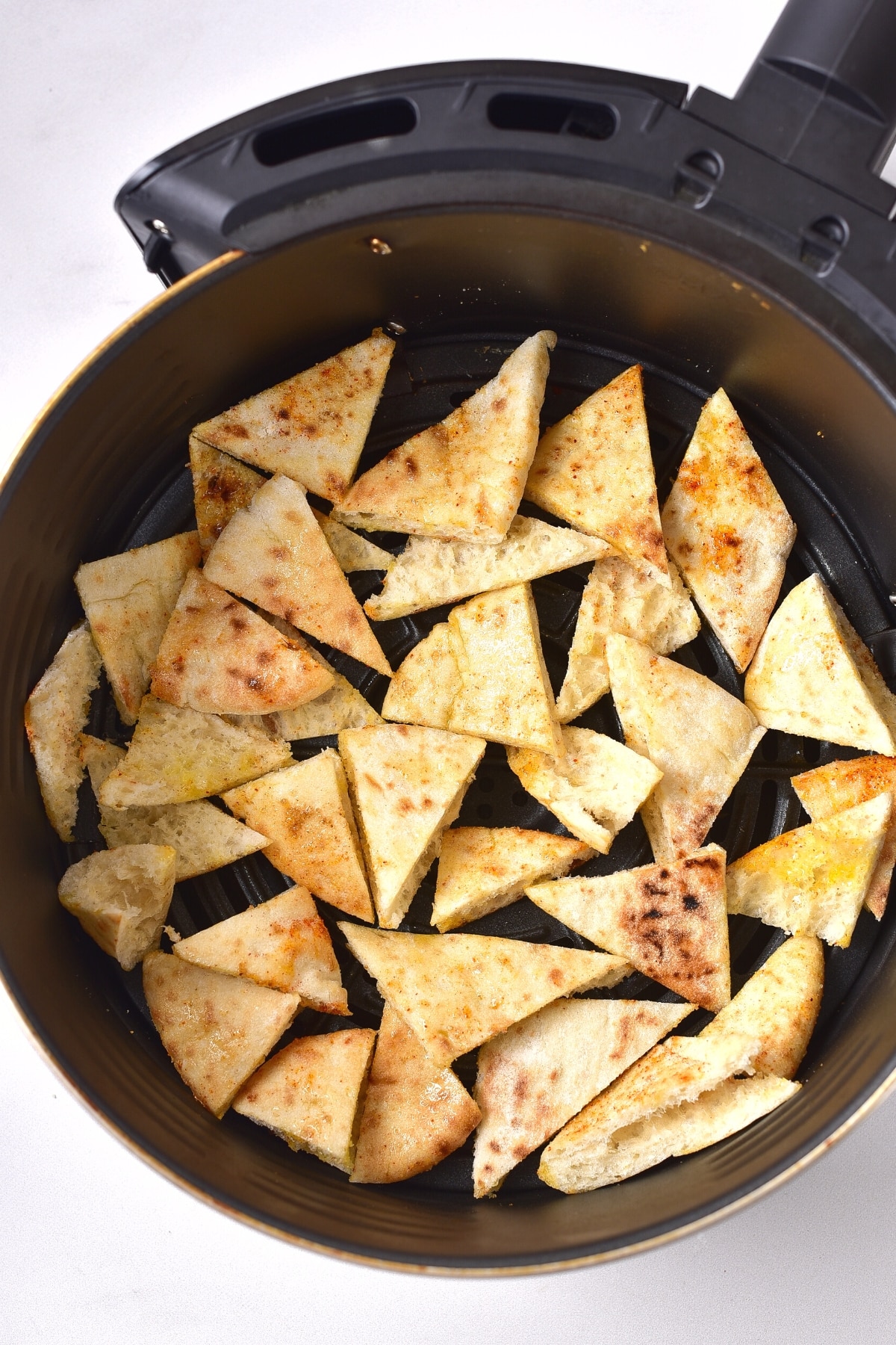 Pita triangles in air fryer basket.