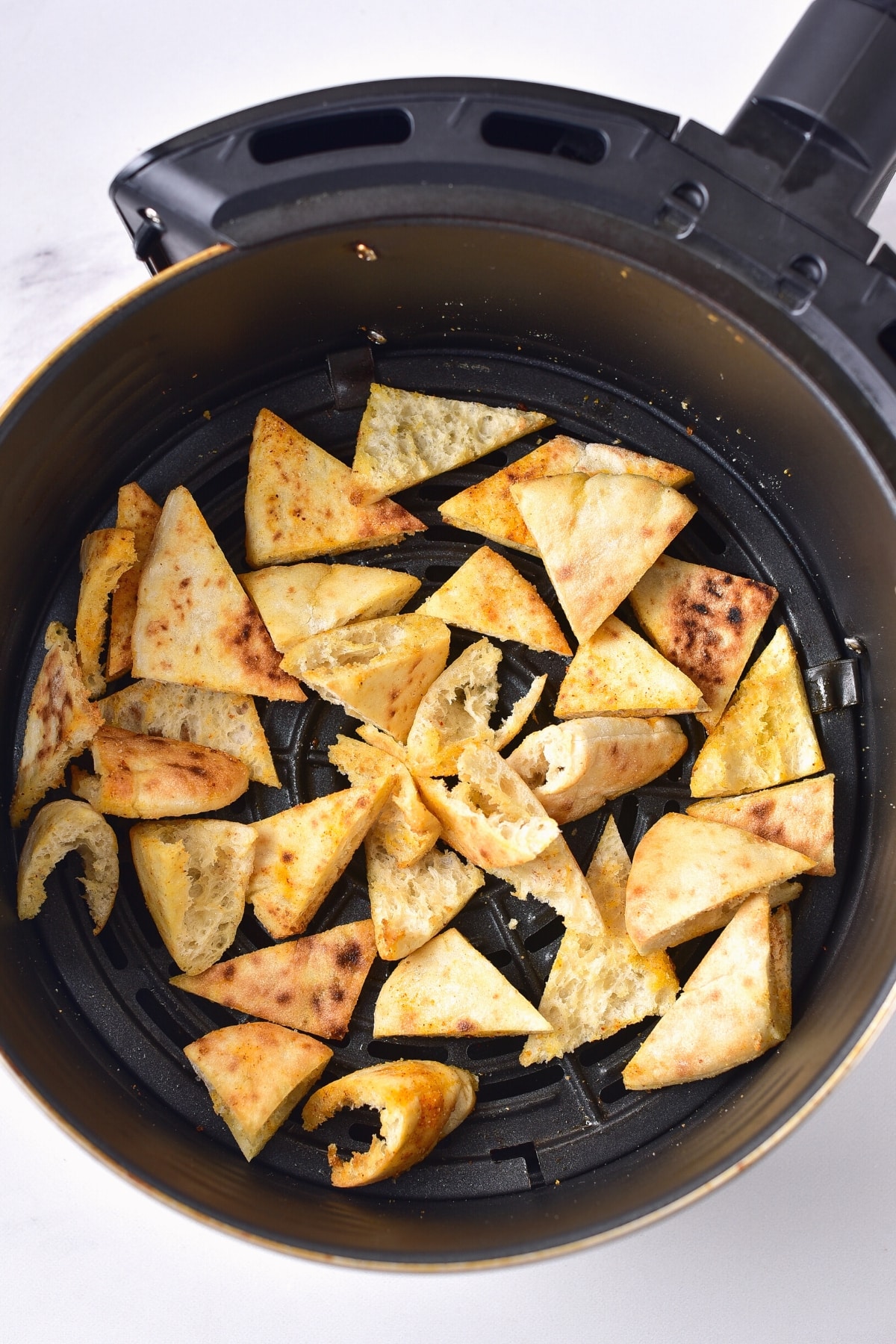 Gluten-free pita toasts in air fryer basket.