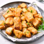 Air fryer salmon bites on a parchment-lined plate.