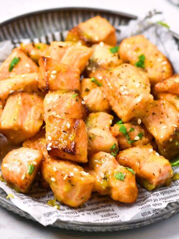 Air fryer salmon bites on a parchment-lined plate.
