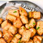Top down view of salmon pieces on parchment-lined plate