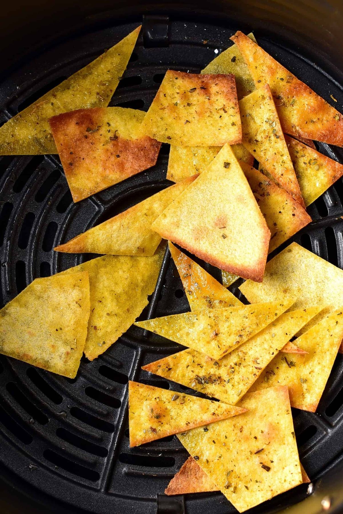 Homemade tortilla chips in air fryer basket.