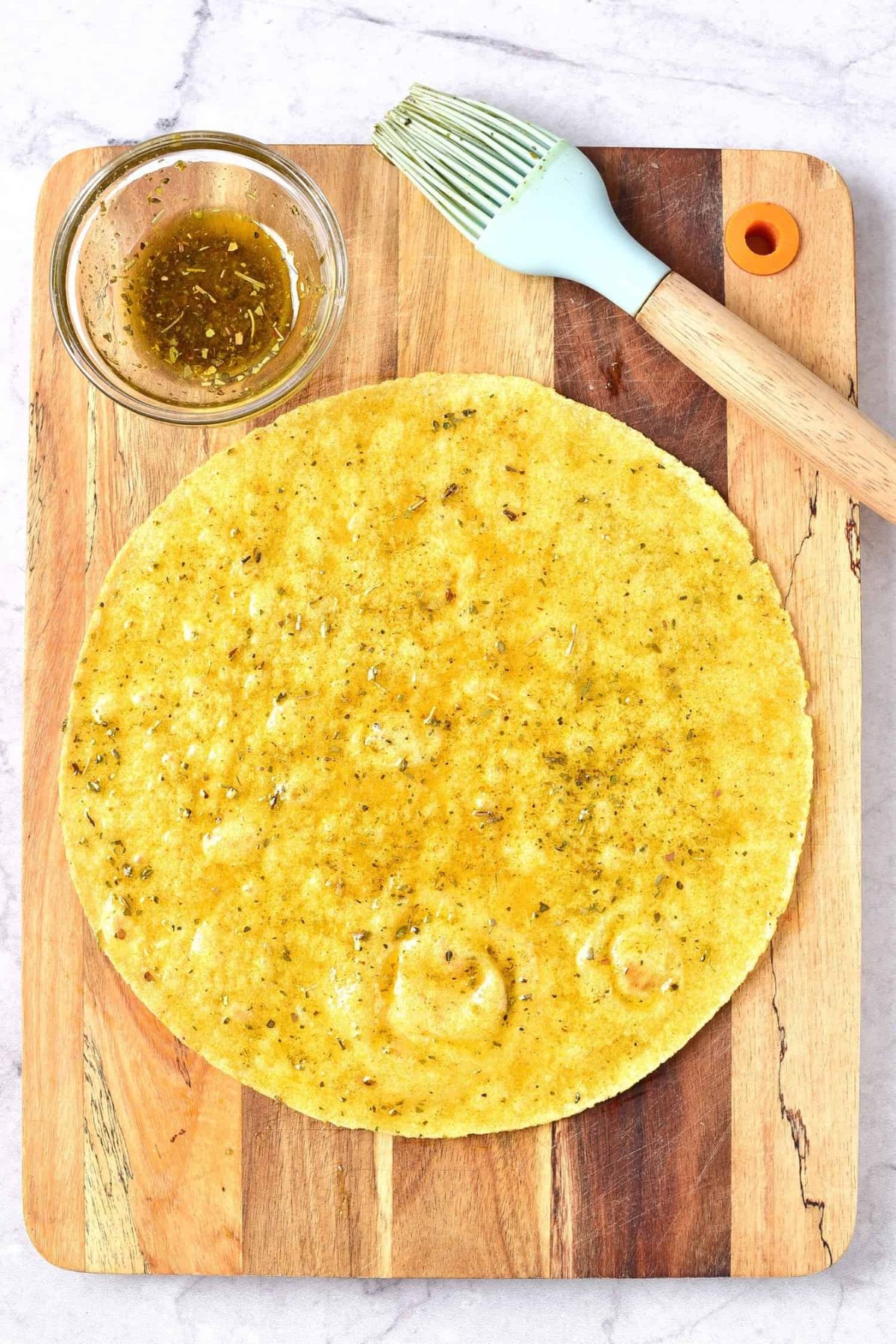 Corn tortilla and brush on wooden board.
