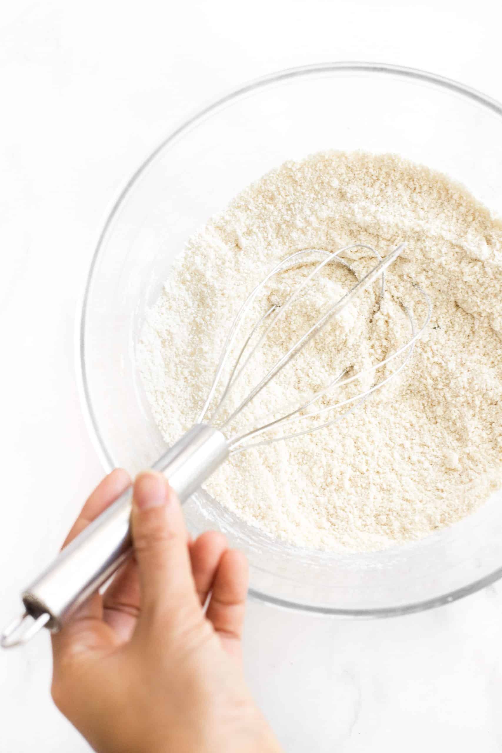 Whisking flour in a glass mixing bowl.