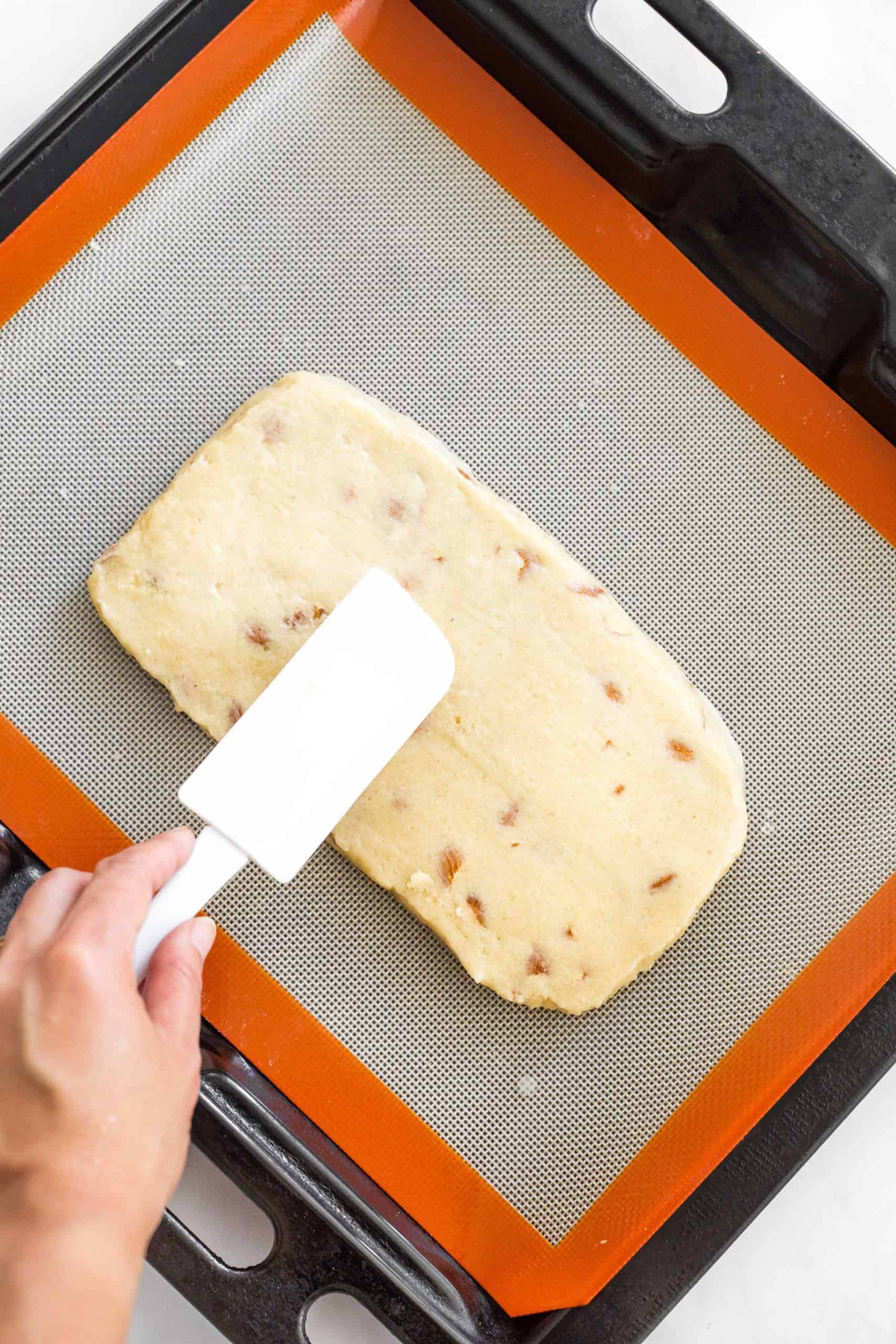 Smoothing the top of a rectangle dough log with a spatula.