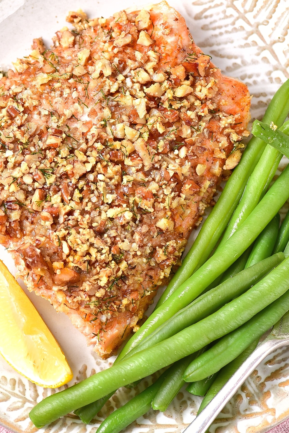 Top down view of a plate of almond crusted salmon with green beans.