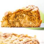 Holding up a slice of apple almond cake from a cake stand