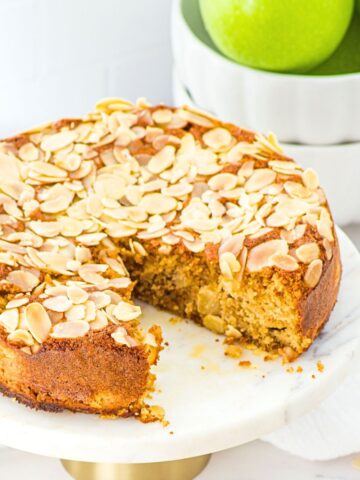 Half-eaten almond flour apple cake with green apples in background