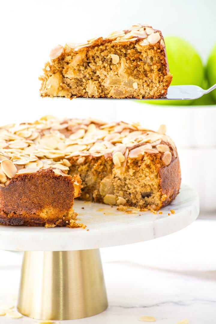 Holding up a slice of apple almond flour cake from cake stand