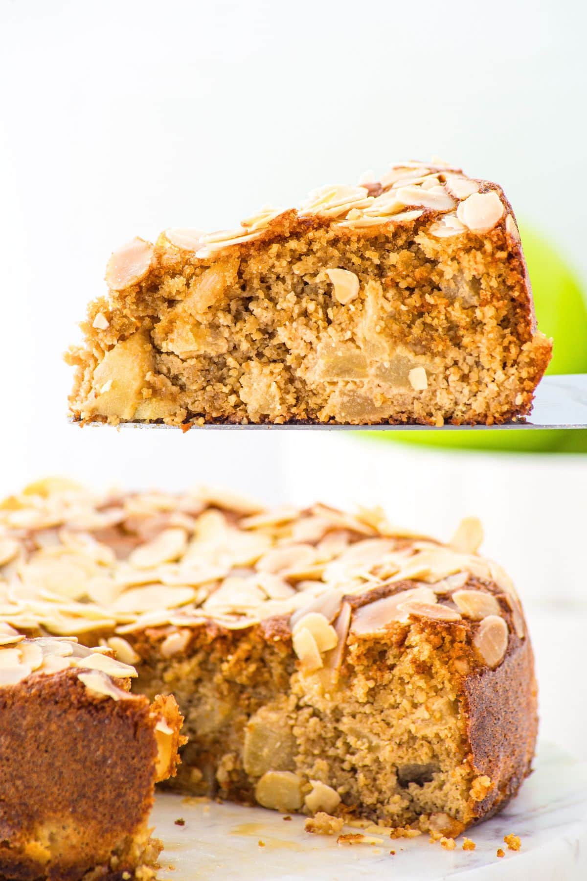 Almond Flour Apple Cake (Gluten-Free, Dairy-Free) Holding up a slice of almond flour apple cake from a whole cake