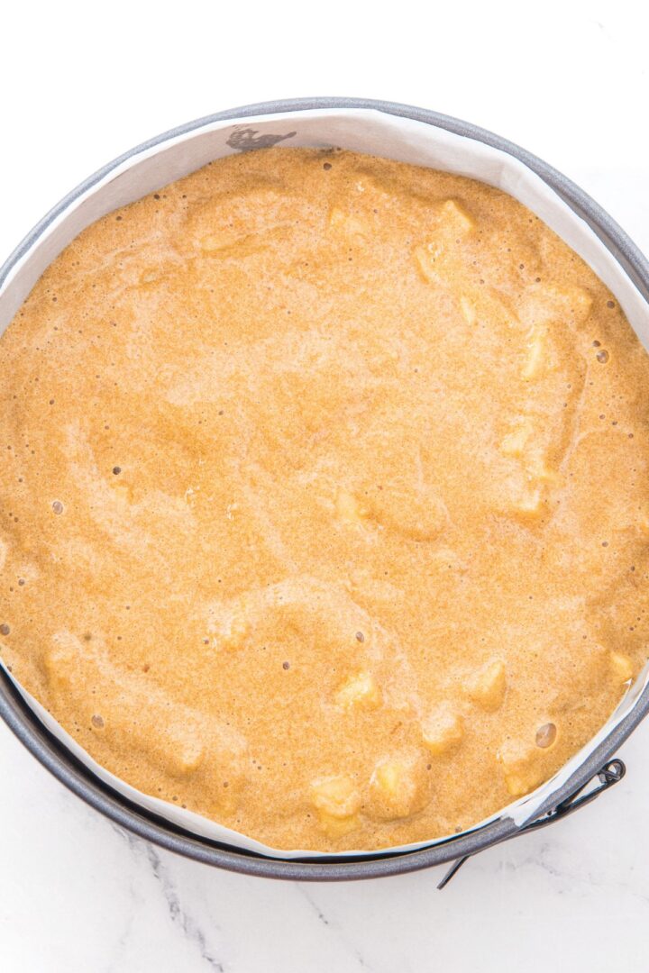 Apple almond flour cake batter in parchment-lined round cake pan