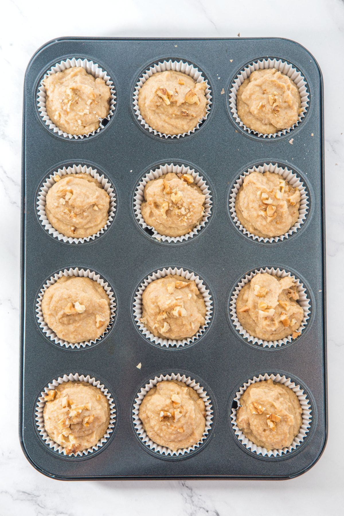 Muffin batter in paper-lined muffin pan