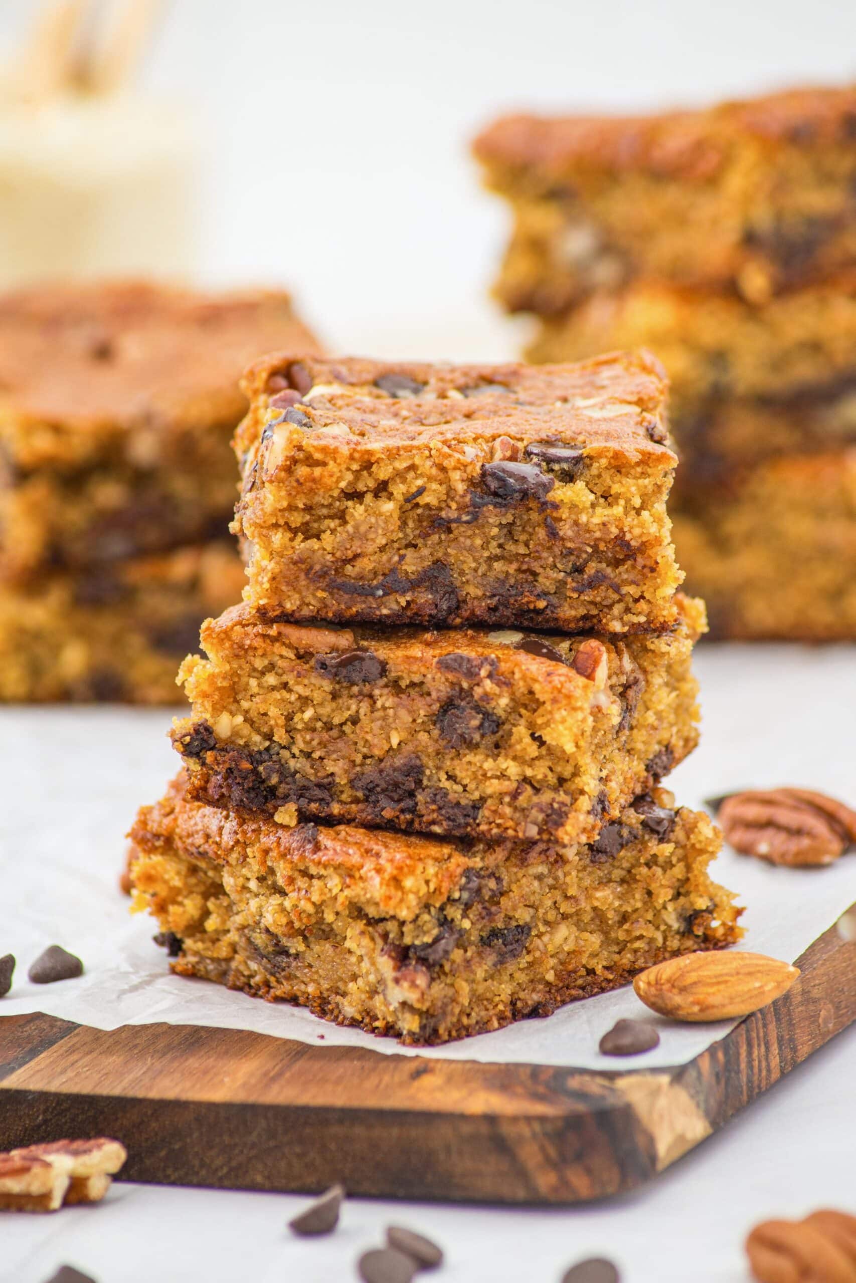 A stack of almond flour blondies on parchment-lined wooden board.