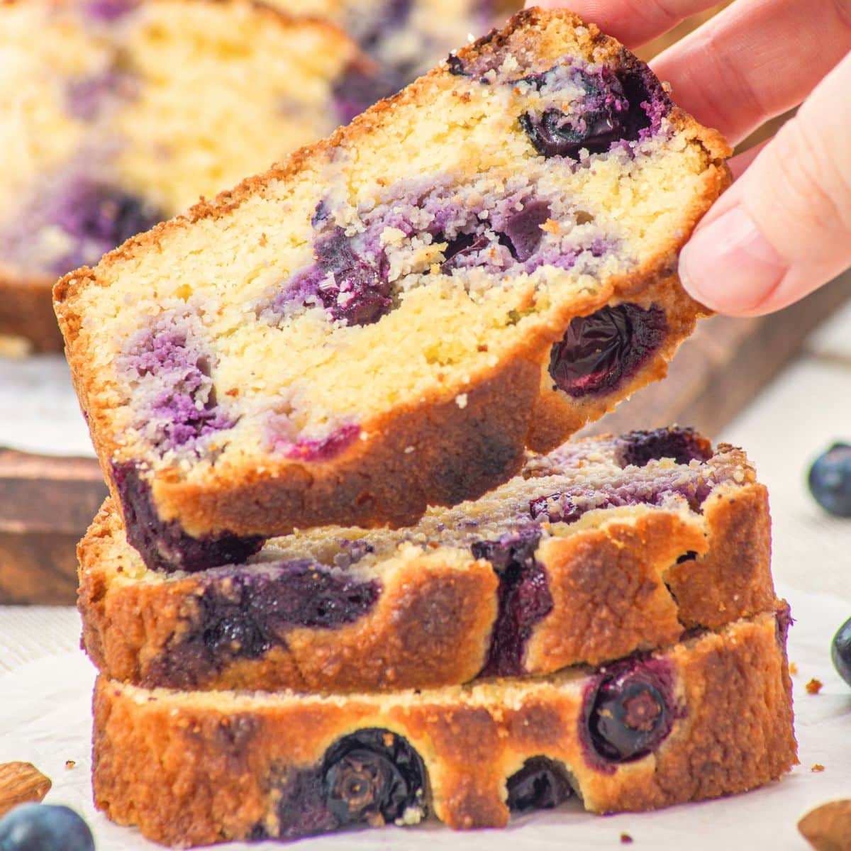 Hand holding up a slice of almond flour blueberry bread