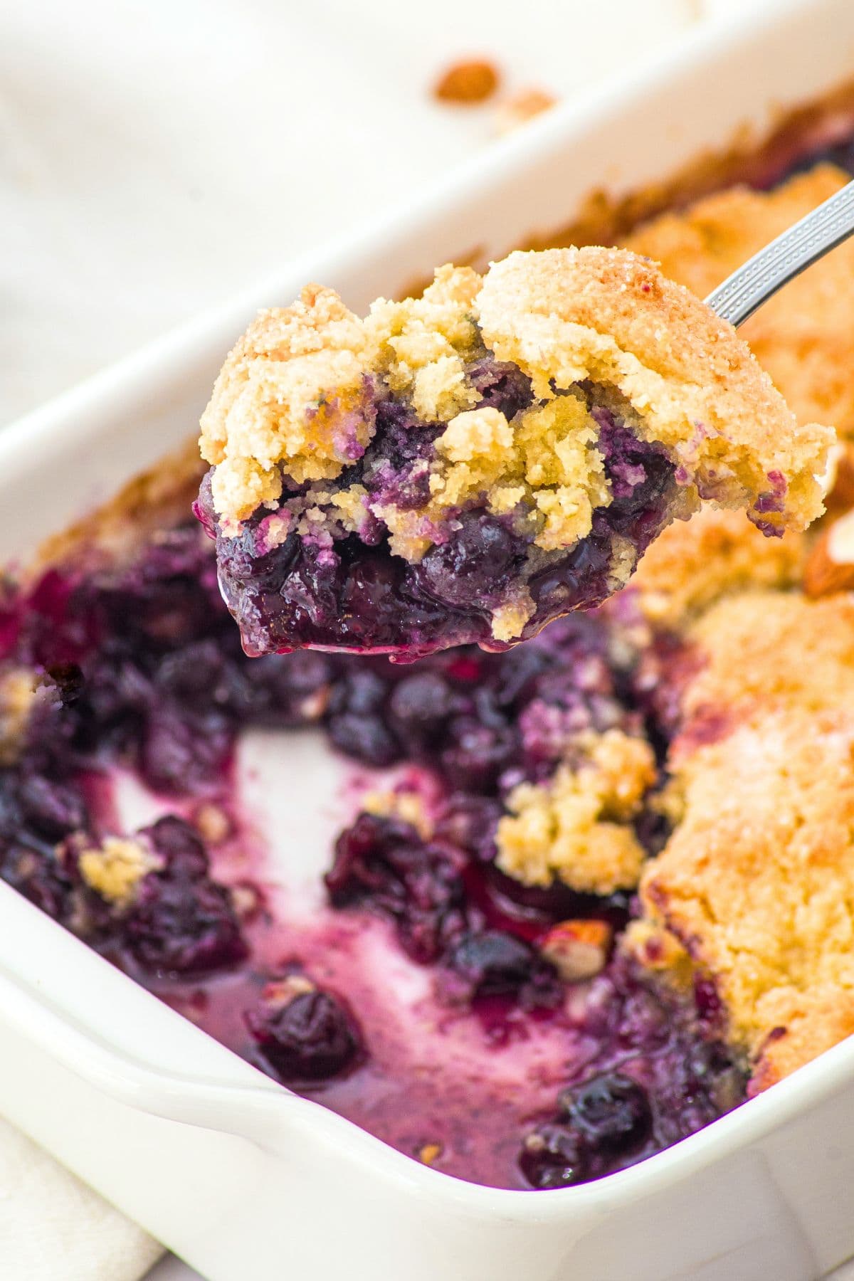 Holding up a spoonful of blueberry cobbler with almond flour.