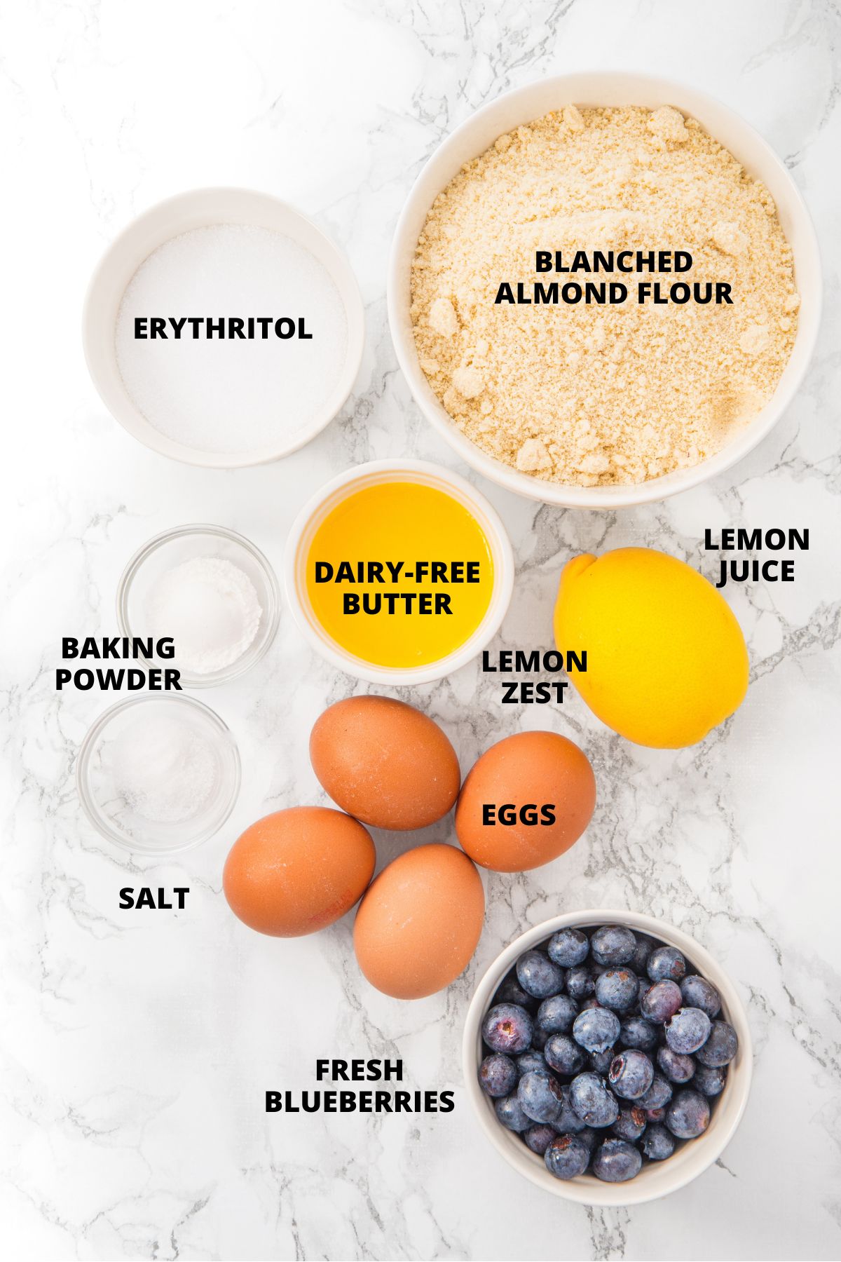 Ingredients for almond flour blueberry muffins laid out on marble board.