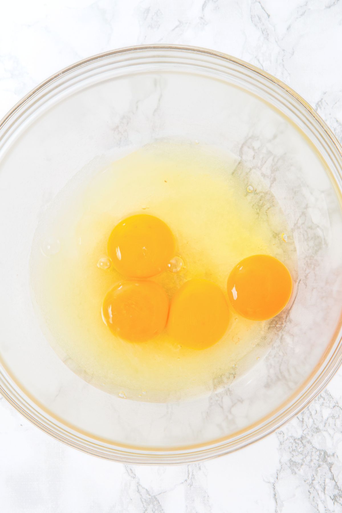 Raw eggs and sweetener in glass bowl