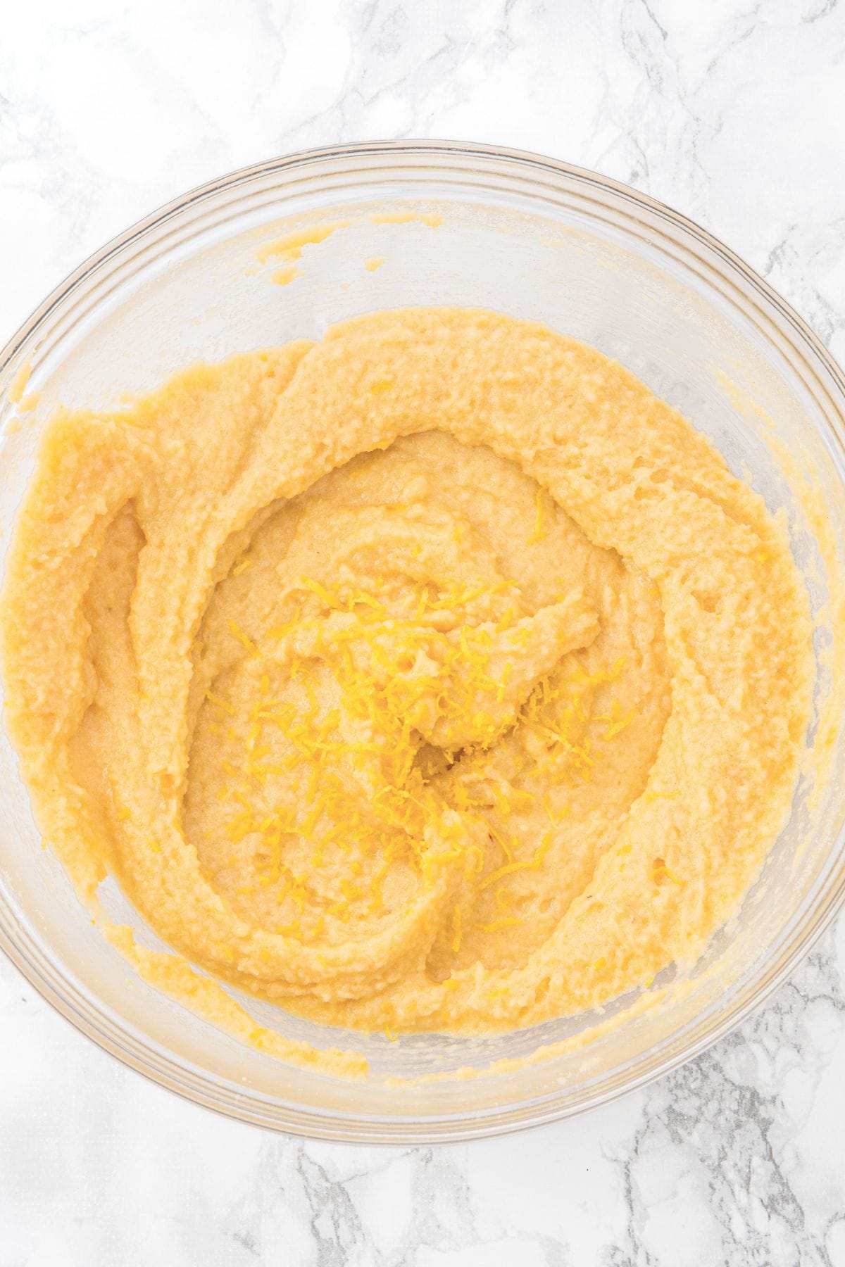Grated lemon zest on top of a bowl of almond flour muffin batter