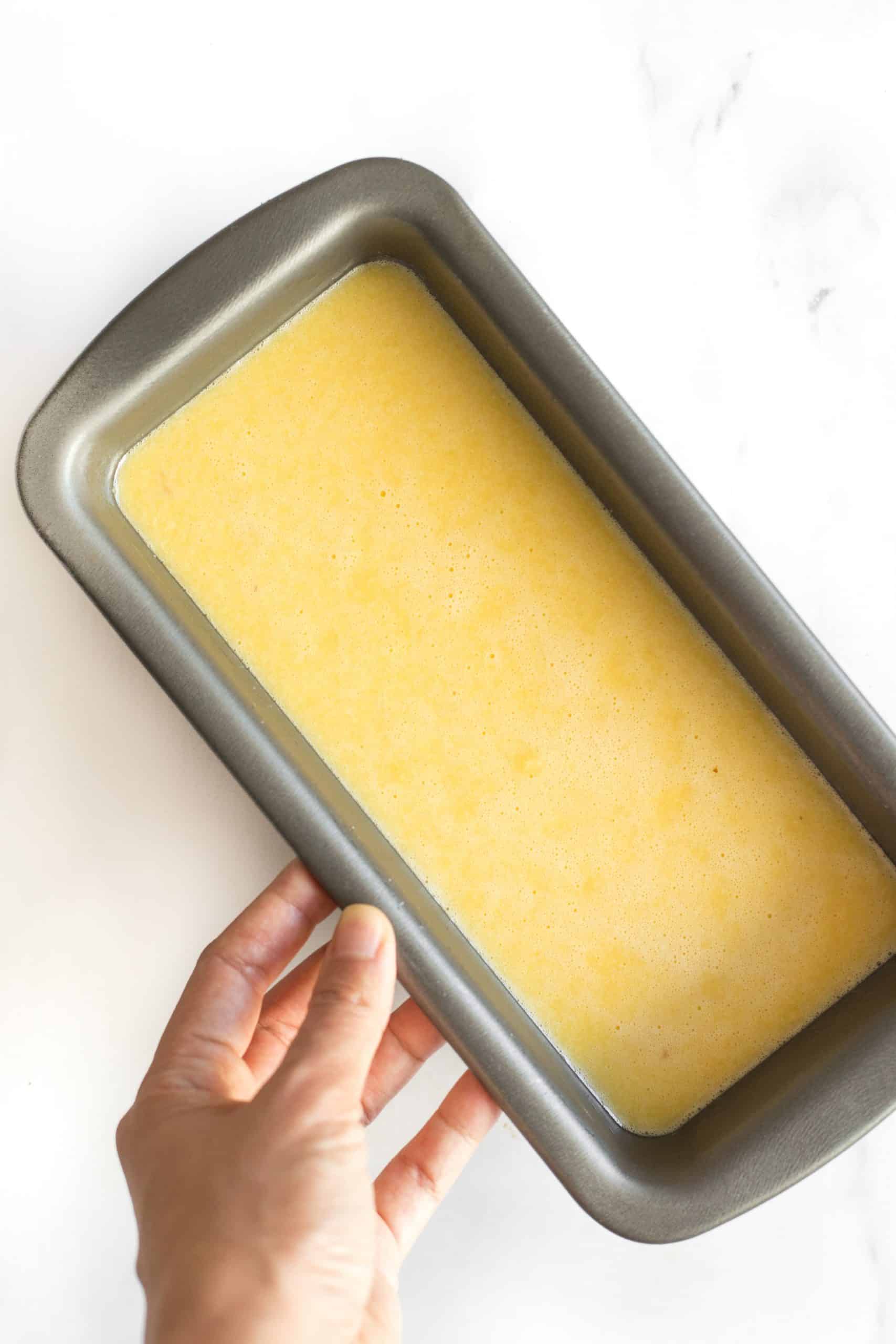 Holding a loaf pan with almond bread batter.