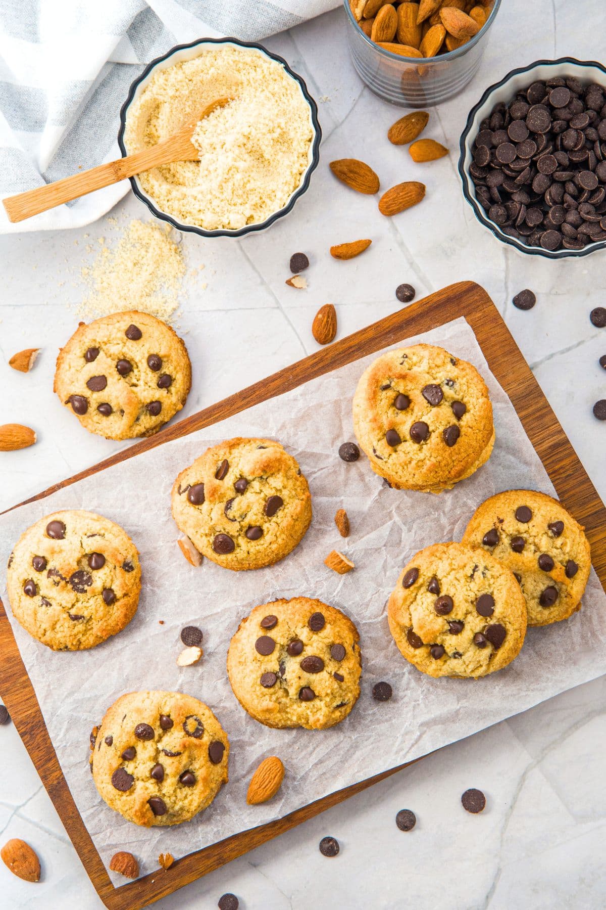 Top down view of chocolate chip cookies with almond flour on parchment-lined wooden board.