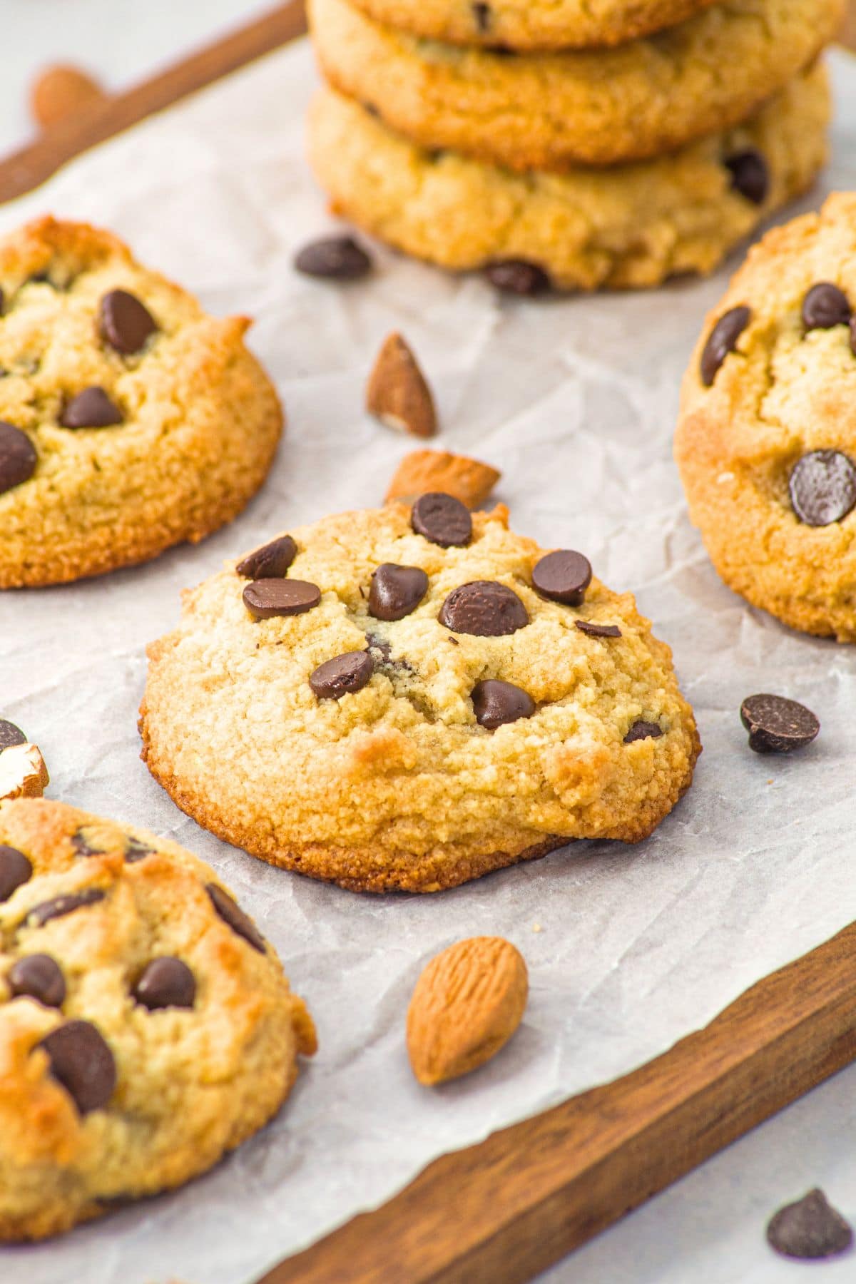 Up close view of almond flour chocolate chip cookies on parchment-lined wooden board.