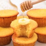 Drizzling honey over a stack of almond flour corn muffins