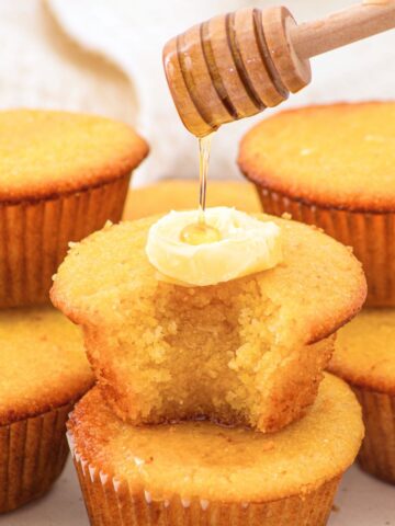 Drizzling honey over a stack of almond flour corn muffins