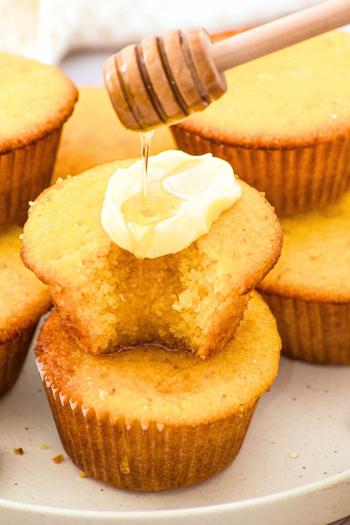 Drizzling honey over butter-smeared almond flour corn muffins.
