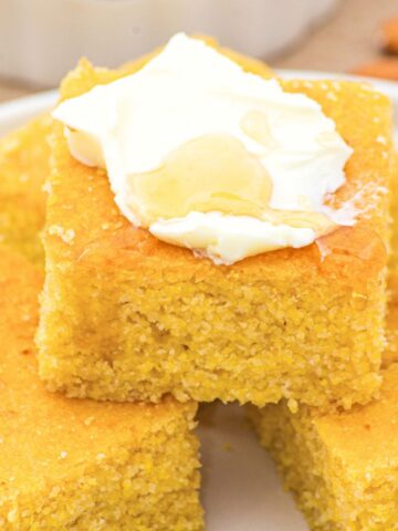 Up close view of almond flour cornbread topped with whipped cream and honey.