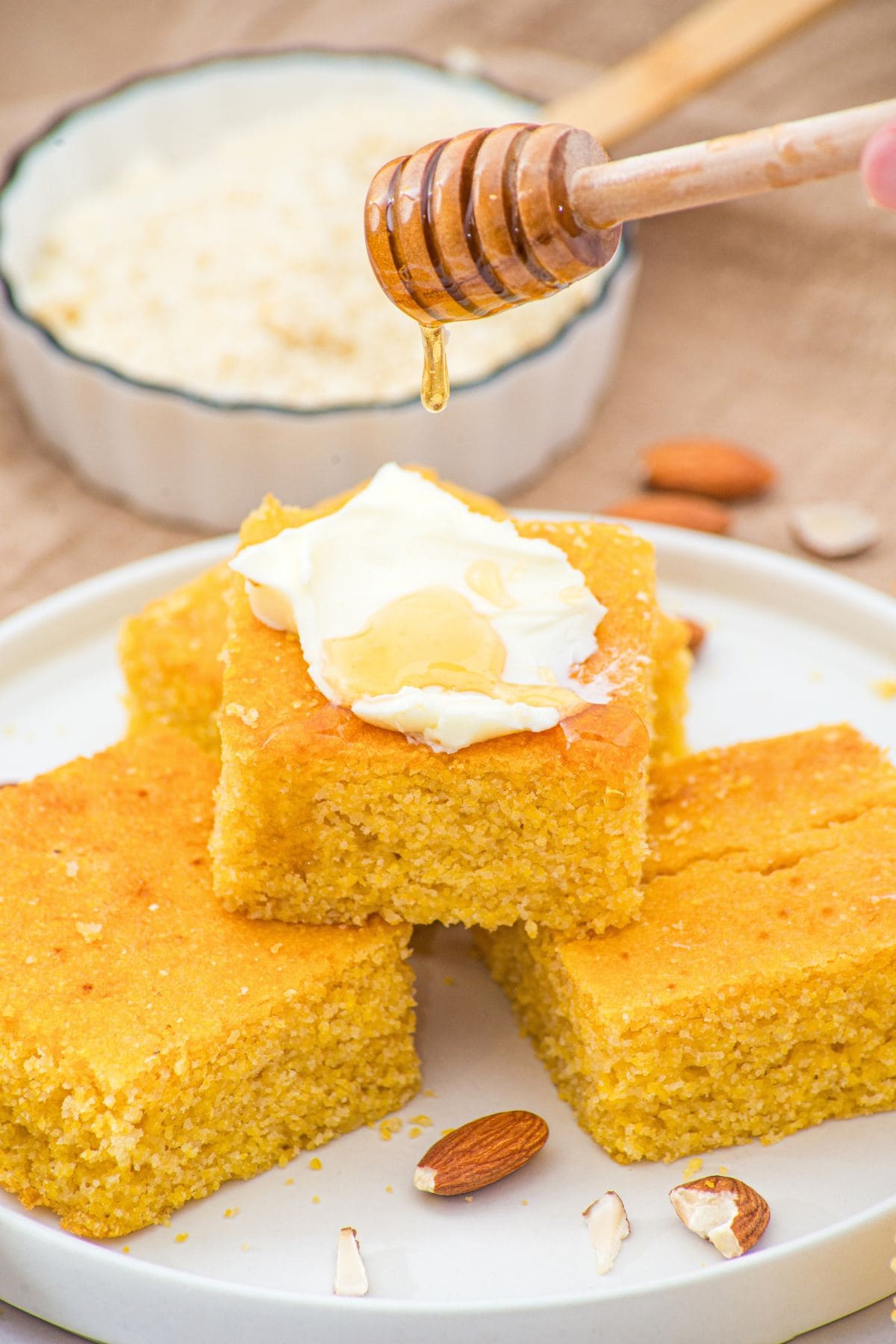 Drizzling maple syrup over almond flour cornbread spread with butter.