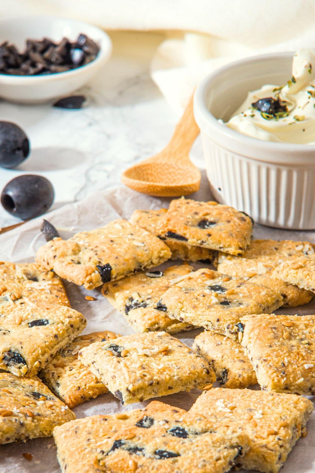 Almond flour crackers on parchment-lined wooden board with cream cheese dip.