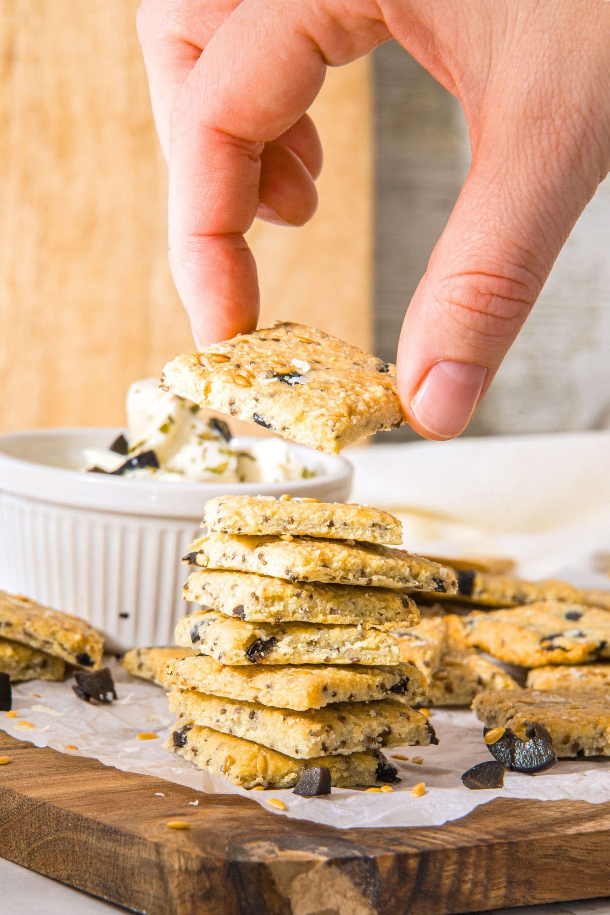 Hand holding up a cracker from a stack of gluten-free almond flour crackers